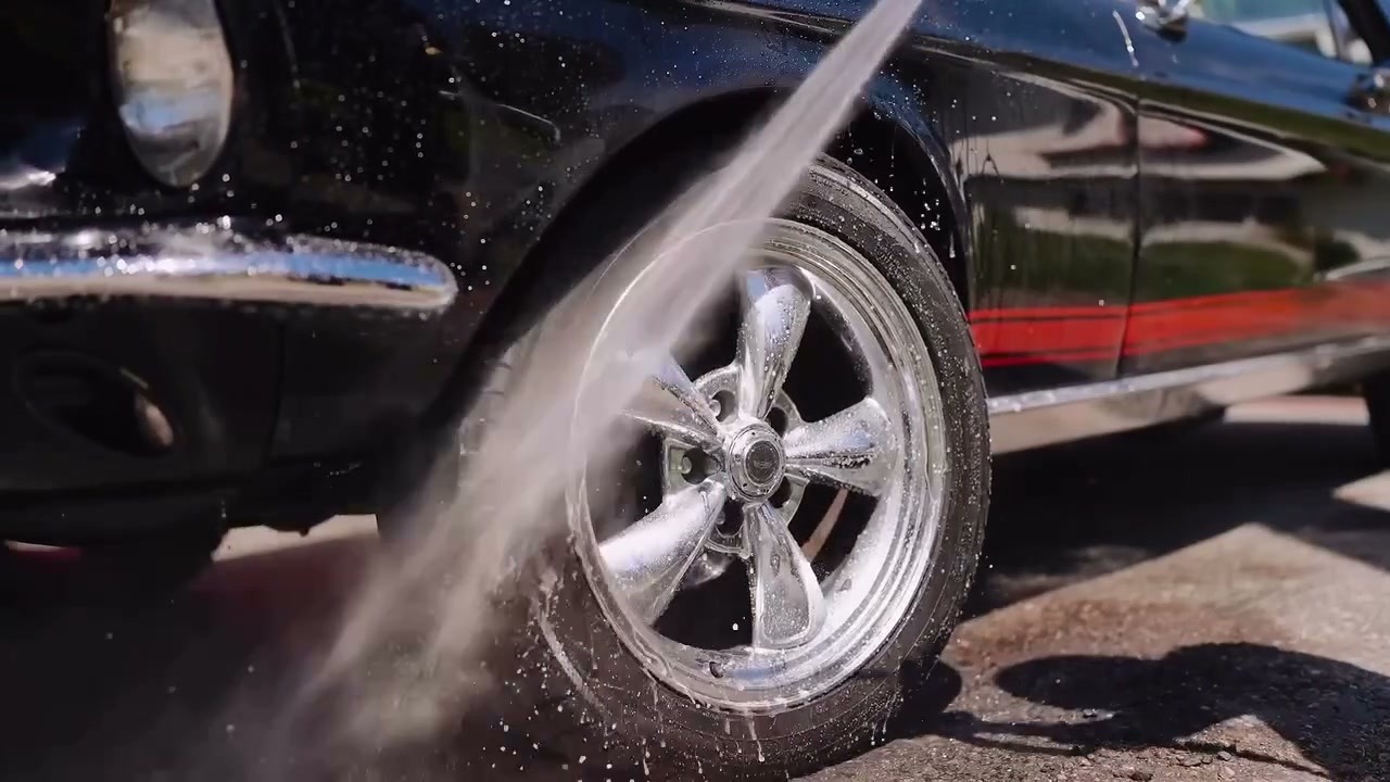 Technician using a dual-action polisher on the deep blue hood of a luxury vehicle